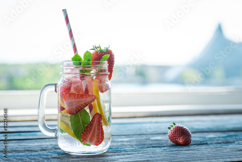 Bilde på lerret Jug with lemon and strawberry infused water on a rustic wooden surface