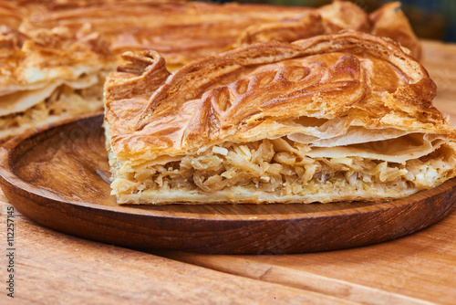 A piece of pie with filling their cabbage on wooden plate