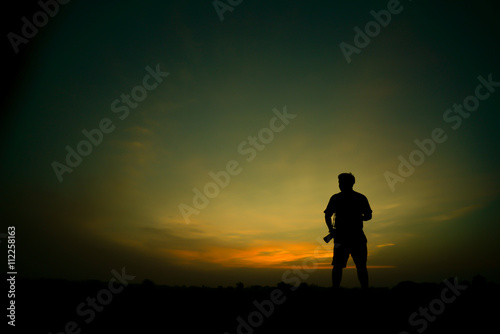 silhouette of man by holding camera at sunrise
