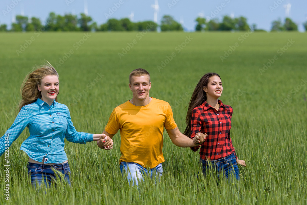 Young happy Friends running on green wheat field Young happy Friends running on green wheat field
