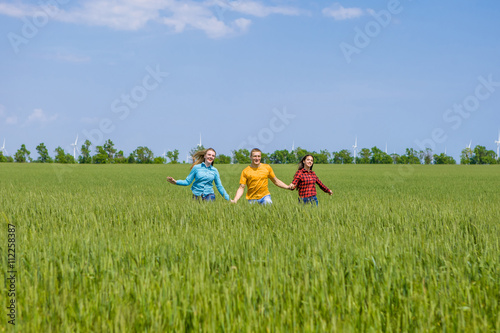 Young happy Friends running on green wheat field