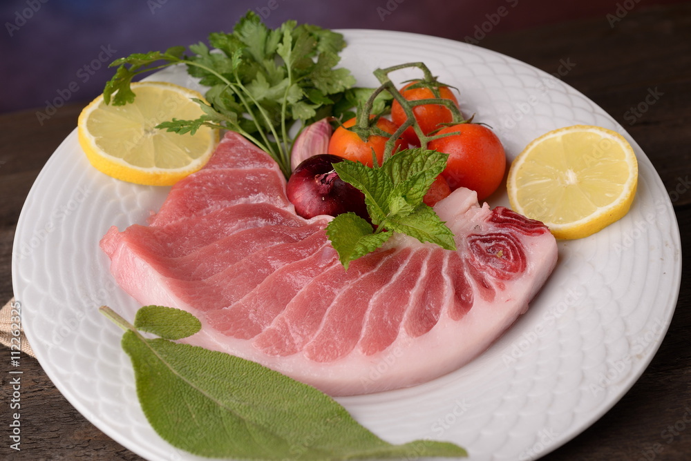 tuna steak raw on white plate with herbs and lemon tuna steak raw on white plate with herbs and lemon