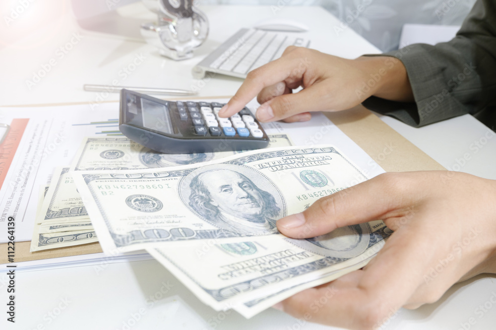 Fototapeta premium business woman hold money dollar with calculator on tablet as fi