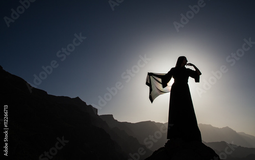 a woman in traditional Emirati dress (abaya) in mountains of Oman photo