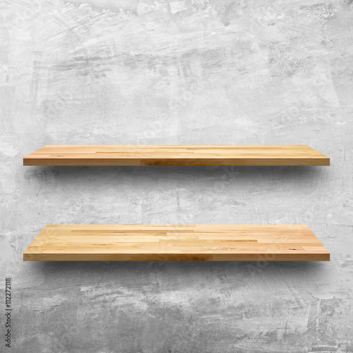Empty wooden bookshelves on bare concrete wall background