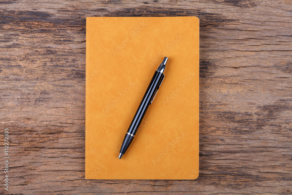 Blank yellow note pad with pen on wood background Blank yellow note pad with pen on wood background