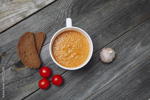 Fototapeta Naklejka Na Ścianę i Meble -  Tomato gazpacho soup with bread and garlic in white bowl on wood