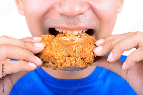 Young man biting fried chicken