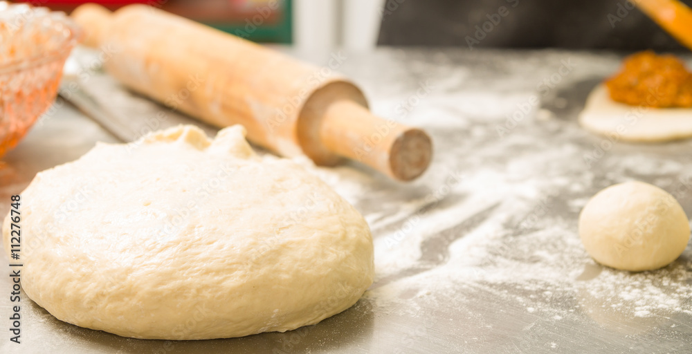 Obraz premium Closeup delicious bread dough shaped as ball before baking, rolling pin background