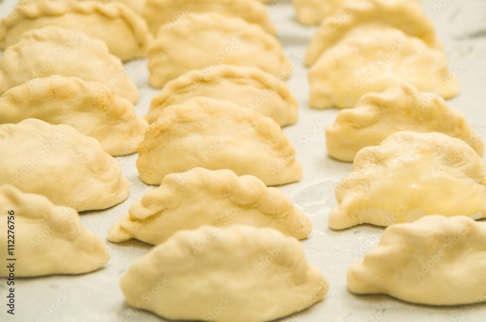 Closeup small delicious empanadas lined up before baking Closeup small delicious empanadas lined up before baking