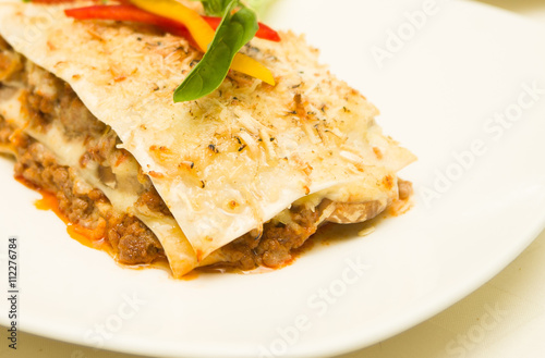 Closeup delicious lasagne serving sitting on white plate, catering concept