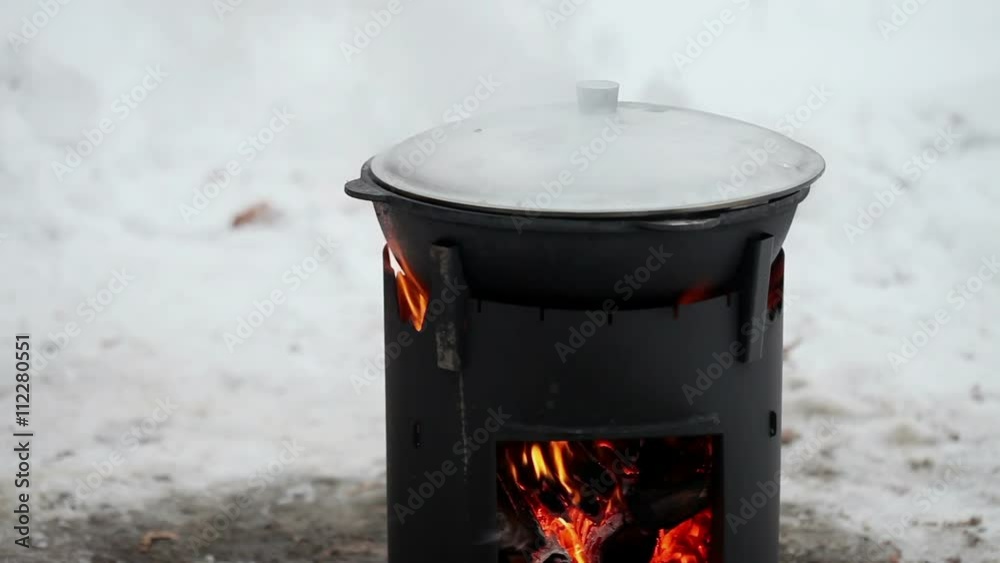 Cooking on a stove in the winter. Cast iron cauldron with a lid on a wood stove Cooking on a stove in the winter. Cast iron cauldron with a lid on a wood stove