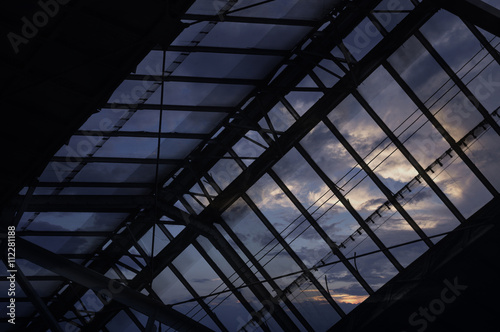 Glass roof detail of Bangkok train station over sunset sky with