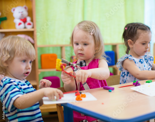 Kids or children creating arts and crafts in kindergarten. Girl is communicating with boy.