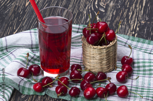 Cherry basket and juice on wooden background
