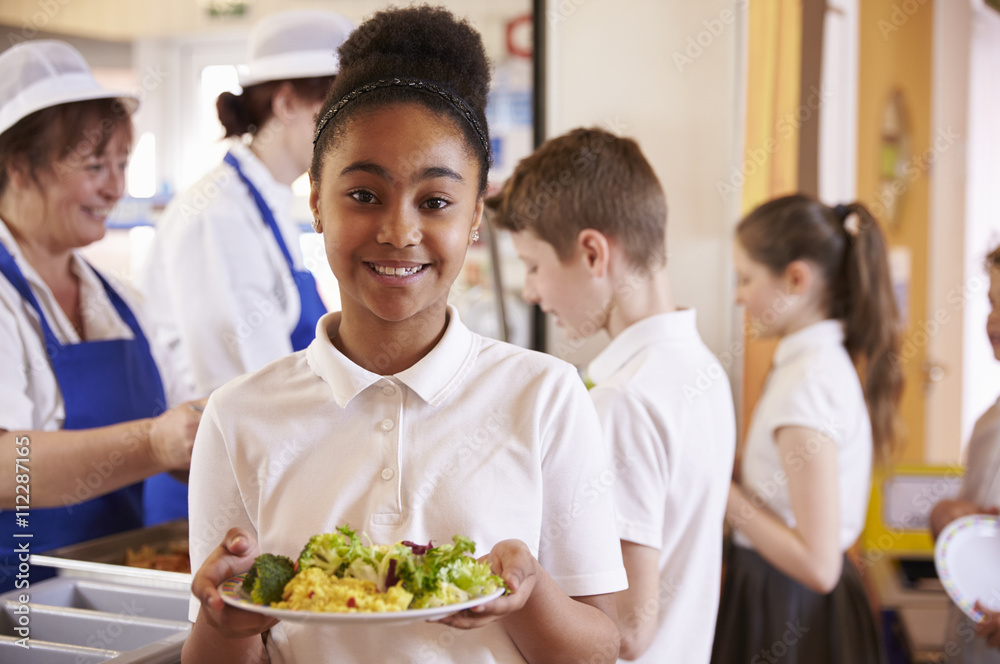 Black schoolgirl holds a plate of food in a school cafeteria Black schoolgirl holds a plate of food in a school cafeteria