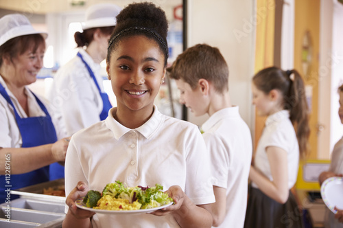 Black schoolgirl holds a plate of food in a school cafeteria