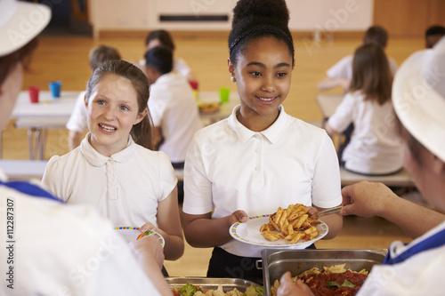 Over shoulder view of girls being served in school cafeteria photo