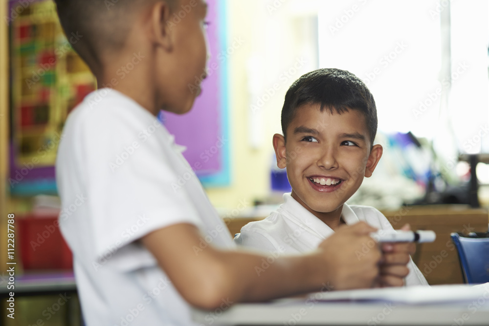 Close up of two primary school boys interacting in class Close up of two primary school boys interacting in class