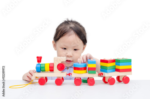 Little asian girl playing with wooden train toy over white