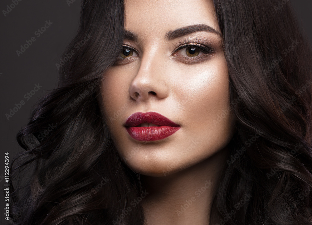 Beautiful brunette model: curls, classic makeup and red lips. The beauty face.