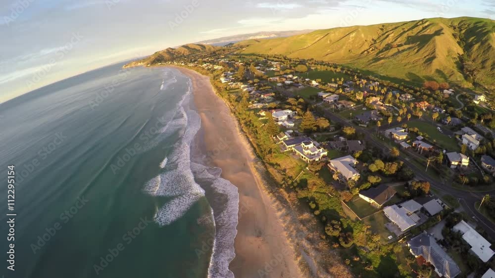 Surfing waves on sandy coastline at Wainui Beach, Gisborne, New Zealand