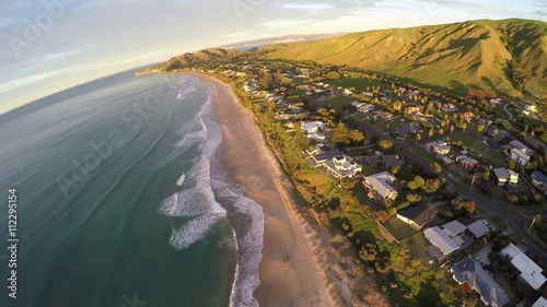 Surfing waves on sandy coastline at Wainui Beach, Gisborne, New Zealand
