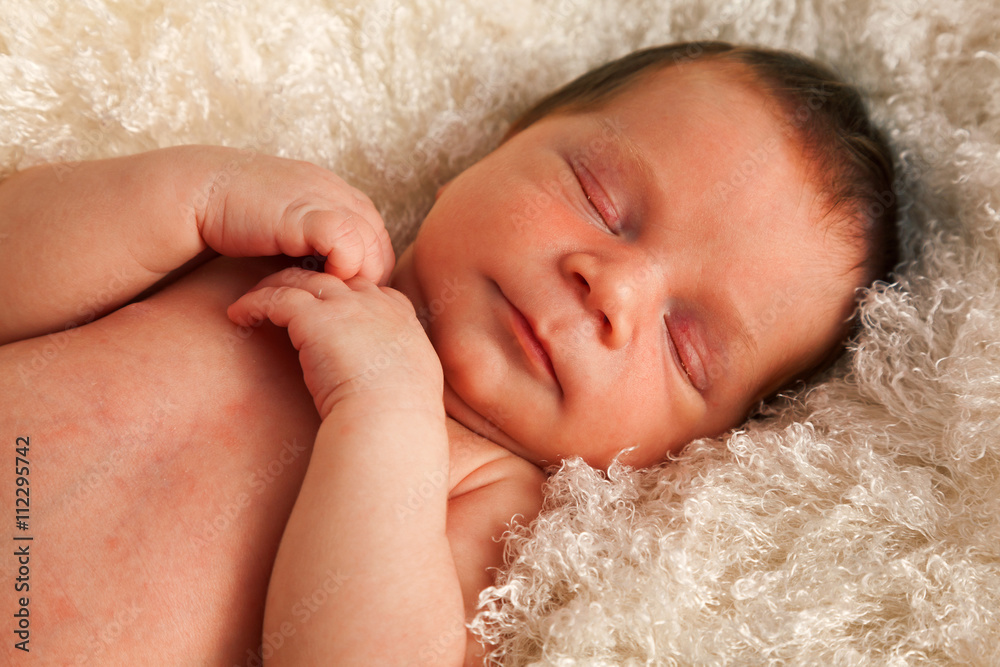 One week old baby sleeping on white blanket. Crossed hands, horizontal shot. One week old baby sleeping on white blanket. Crossed hands, horizontal shot.
