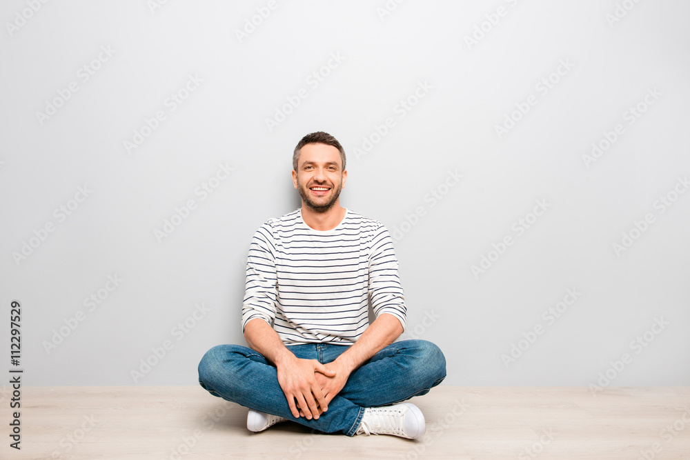 Cheerful happy man sitting on floor with crossed legs Cheerful happy man sitting on floor with crossed legs