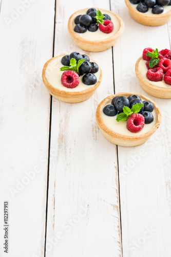 Delicious tartlets with raspberries and blueberries
on white wood