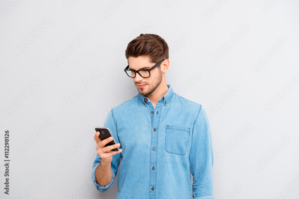 Portrait of young guy in spectacles reading message on phone Portrait of young guy in spectacles reading message on phone