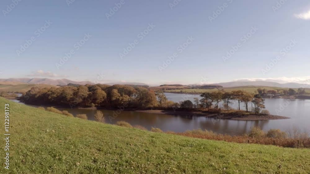 Zoom in on scenic English lake landscape as man walks into frame to enjoy the view Zoom in on scenic English lake landscape as man walks into frame to enjoy the view