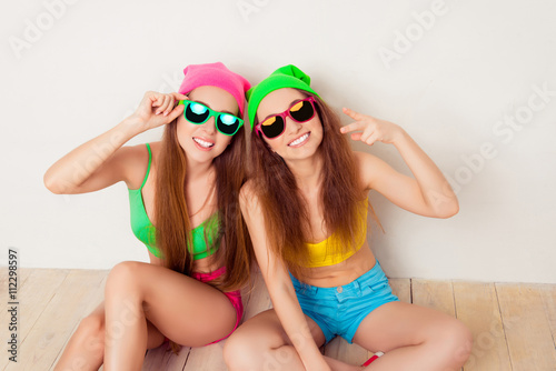 Portrait of hipster women in caps and glasses siting on floor photo