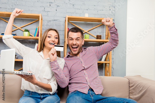 Cheerful family making internet shopping with laptop and bank ca photo