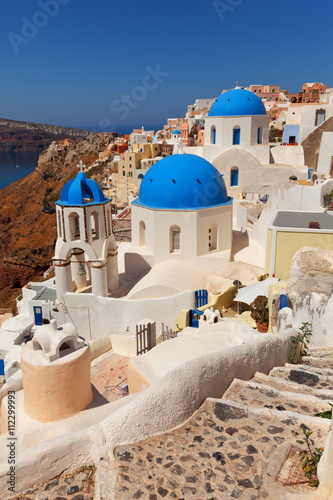 Landscape of Oia town in Santorini, Greece with blue dome churches and stairs on foreground.