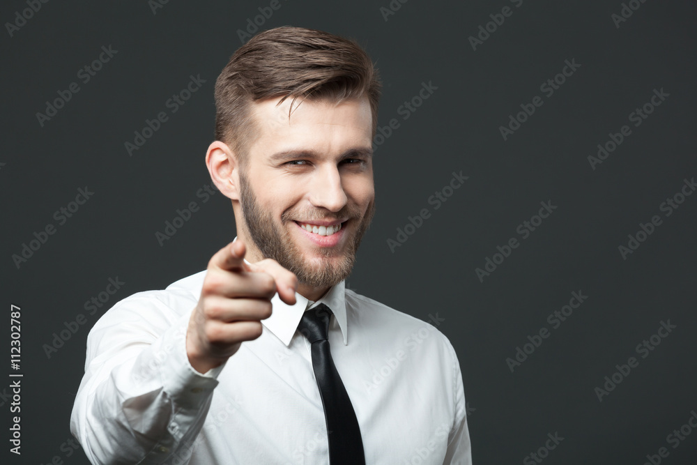 Young handsome businessman pointing at you isolated on gray bac Young handsome businessman pointing at you isolated on gray bac