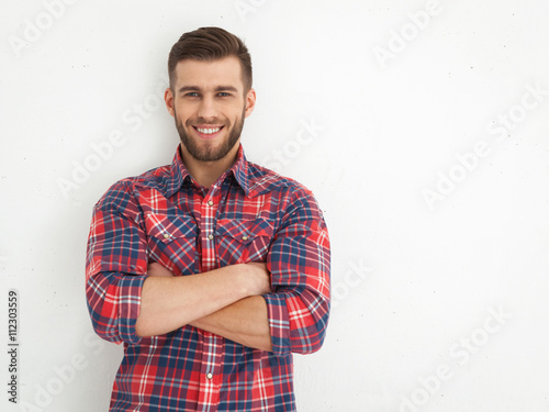 Handsome young guy standing against white wall.