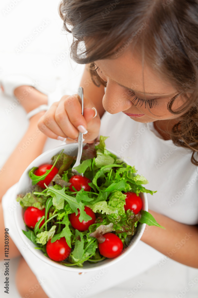 Young woman eating healthy salad. High angle, vertical shot.