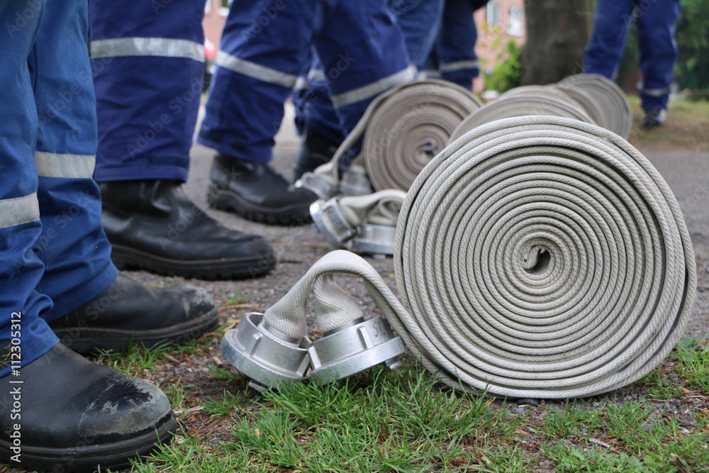 Obraz premium Feuerwehrschlauch liegt zum Einsatz bereit - Jugendfeuerwehr übt mit Feuerwehrschlau