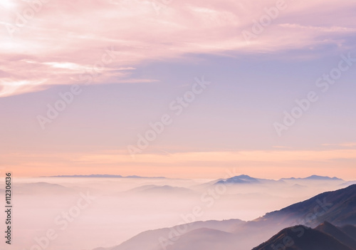 Sky clouds above misty European alps before sunset