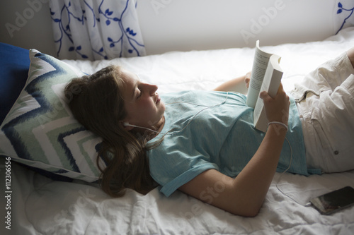 girl lying on bed and reading book.