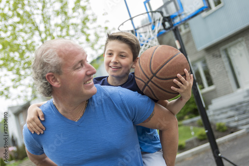 Image of young man and his son playing basketball