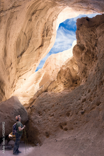 A tourist looks at the sky through a crack in a narrow canyon.