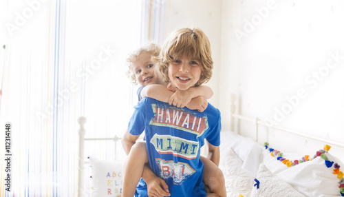 Boy giving his little brother a piggyback ride at home photo