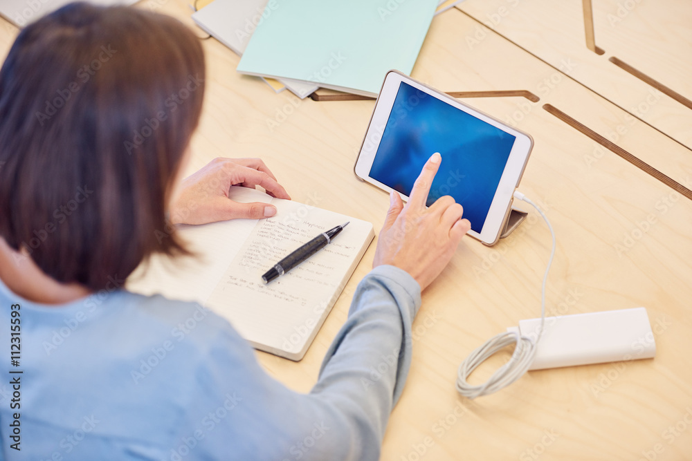 over the shoulder shot of woman unlocking her tablet