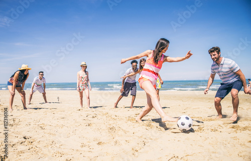 Friends playing football on the beach