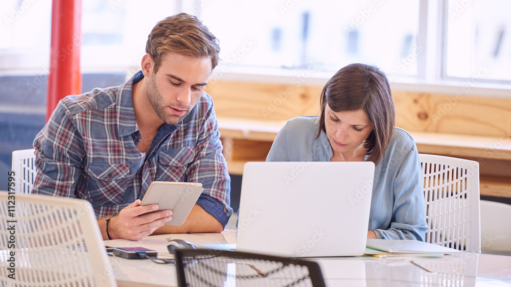 Adult male and female business partners busy working in office Adult male and female business partners busy working in office