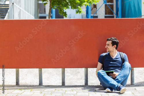 Smiling young  student man taping on tablet  using tablet in campus university.Young smiling student outdoors with tablet.Life style.City