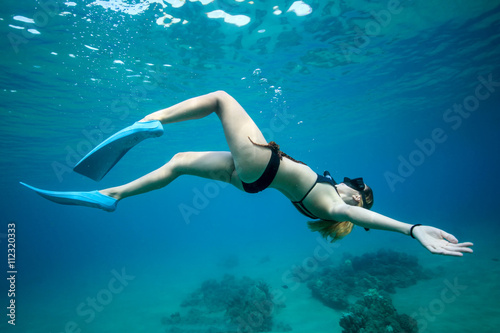 Young woman swimming with snorkel and mask underwater at tropical sea