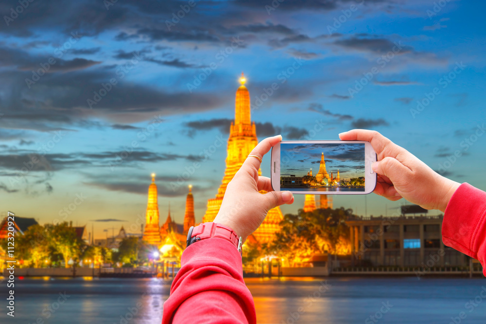 Fototapeta premium Smartphone photographing Wat Arun Buddhist religious places in twilight time, Bangkok, Thailand